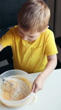 Çocuk çanakta malzeme çırpıyor, yemek yapmayı öğreniyor.