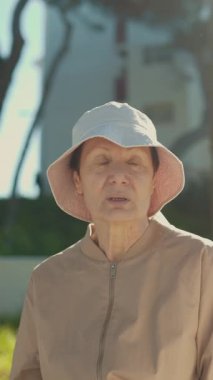 Kovalı şapka takan yaşlı bir kadın parkta genç bir kadını dikkatle dinliyor.