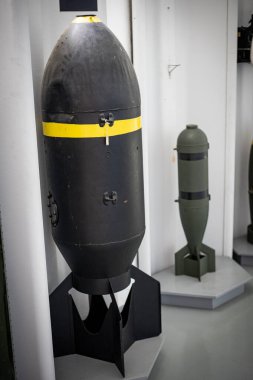 Sarı çizgili büyük siyah bomba müze vitrininde daha küçük yeşil bir bombanın yanında duruyor.