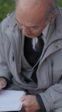 Bir bankta oturan kıdemli bir adam not alıyor.