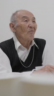 Kıdemli adam konuşuyor, el kol hareketi yapıyor ve atıştırıyor.