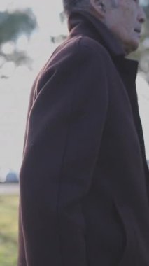 Kıdemli adam yeşil bir parkta huzurlu bir gezinti yapıyor.