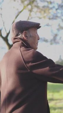 Kıdemli adam parktaki palmiye gövdesini inceliyor.