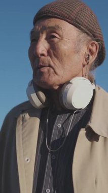 Boynuna kulaklık takan kıdemli Asyalı adam etrafını gözetliyor.