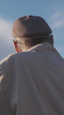 Kulaklık takan son sınıf öğrencisi şehir manzarasına tepeden bakan bir parkta müzik dinliyor.