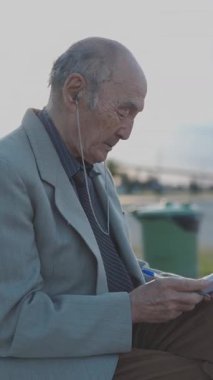 Üst düzey bir adam notlarını yazarken müziğin keyfini çıkarıyor, parktaki bir bankta oturuyor.