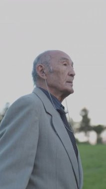 Huzurlu bir parkta rahatlatıcı bir yürüyüş sırasında kıdemli işadamı müziğin keyfini çıkarıyor.
