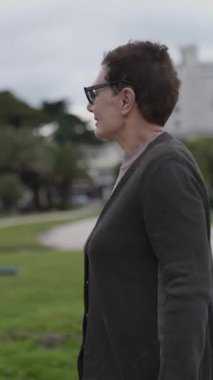 Kıdemli kadın parkta rahatça dolaşmaktan, doğayla etkileşimden ve manzaranın tadını çıkarmaktan hoşlanır.