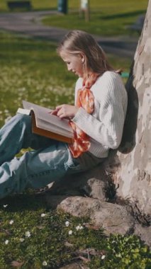 Öğrenci açık havada okumayı, güneşli bir parkta bir ağacın altında oturmayı sever.