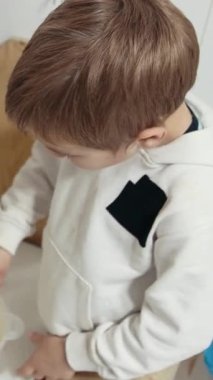 Çocuk malzemeleri bir kasede çırpıyor, mutfakta yemek tarifi hazırlıyor.