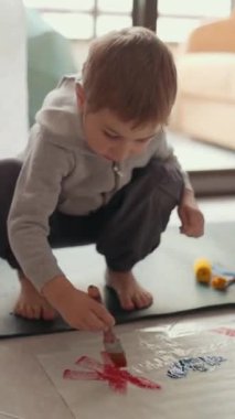 Çocuk yaratıcı oyun zamanını seviyor, yere renkli resimler çiziyor.