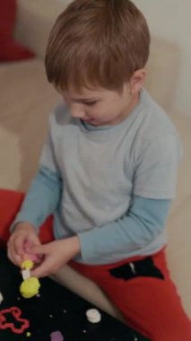 Genç çocuk yaratıcı oyun zamanını seviyor. Masada renkli mankenlik killerini şekillendiriyor.