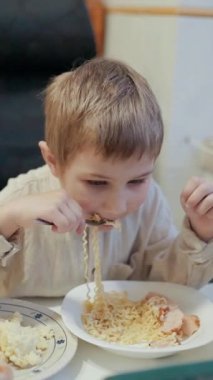 Anaokulu çocuğu, teraryumdaki küçük bir evcil hayvan tarafından izlenen şehriyeyi zevkle yer.