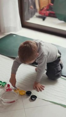 Yaratıcı çocuk yerde parmak boyamaktan zevk alıyor, renkleri keşfediyor ve sanatsal beceriler geliştiriyor.