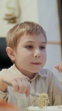 Çocuk hevesle mutfakta erişte yiyor.