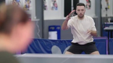 Genç adam bir spor kulübünde pinpon oynarken konsantre oluyor.