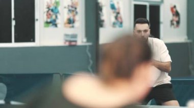 İki genç adam bir spor kulübünde güçlü bir masa tenisi oyunu oynuyor.