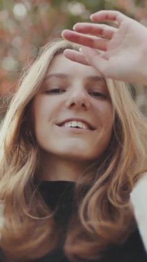 Gençlik saçlarıyla oynuyor ve sonbaharda parkta gülümsüyor.