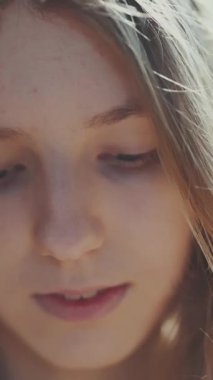 Uzun sarı saçlı, gün ışığında poz veren güzel, gülümseyen genç bir kızın portresi.