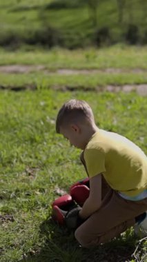 Boks eldivenli çocuk boksörü eğitimi, çayırda bir ağacı yumruklamak.