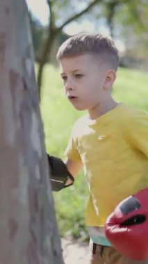 Çocuk ağaç gövdesinde boks antrenmanı yapıyor.