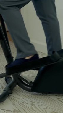 İş adamı evde eliptik bisikletle fitness yapıyor.