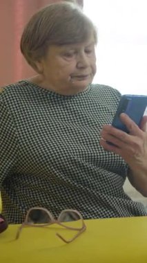 Üst düzey kadın akıllı telefon kullanıyor ve okuma gözlüğü takıyor.