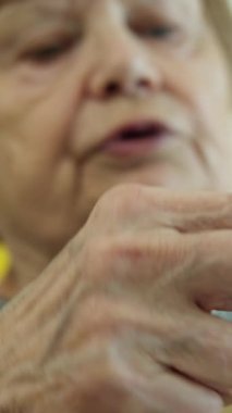 Odaklanmış yaşlı kadın ustalıkla beyaz iplikle örgü örüyor, rahat bir el işi yaratıyor.