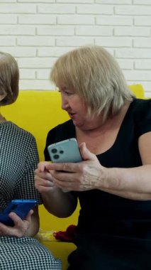 İki son sınıf öğrencisi kanepede oturmuş akıllı telefonlara bakıyor ve bir şeyler tartışıyorlar.