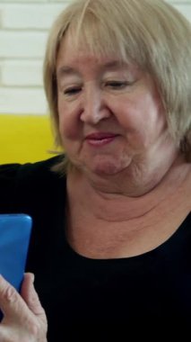 İki son sınıf öğrencisi sarı bir kanepede oturup akıllı telefon kullanarak video görüşmesi yapıyorlar.