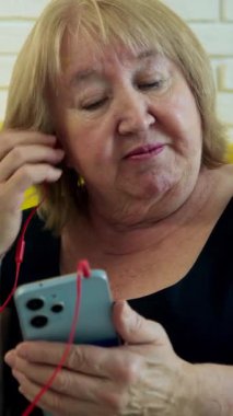 Kulaklık takan, akıllı telefondan müzik dinleyen ve şarkıyı tartışan iki son sınıf öğrencisi kadın.