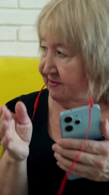 Kulaklıkla müzik dinleyen, akıllı telefonu paylaşan ve gülen iki son sınıf öğrencisi kadın.