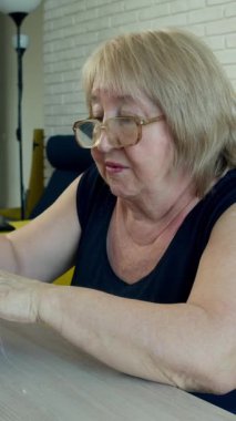 Kıdemli terzi dikiş makinesi kullanıyor ve kıyafet yapıyor.