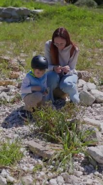 Anne ve oğul kayalık bir arazide doğayı keşfediyorlar.