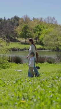Anne ve oğlu ördeklerle çevrili bir gölün kenarındaki gölün keyfini çıkarıyorlar.
