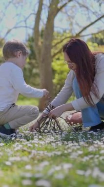 Kızıl saçlı kadın ve oğlu papatya tarlasında dallı küçük bir çadır kuruyorlar.