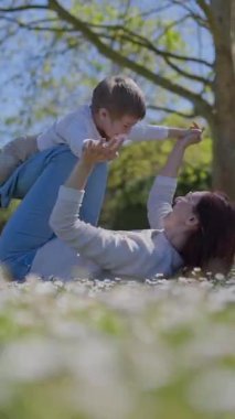 Mutlu anne ve oğul güneşli bir günde papatya tarlasında birlikte oynuyorlar.