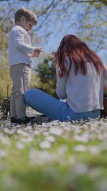 Mutlu anne ve oğul papatya tarlasında güneşli bir günün tadını çıkarıyor.