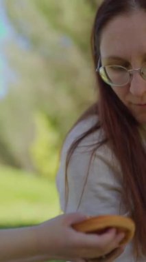 Anne ve oğlu güneşli bir parkta piknik yaparken hamburger yiyorlar.