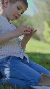 Çocuk, annesi yakınlardayken parkta atıştırmanın tadını çıkarıyor.