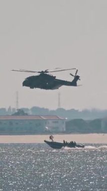 Askeri helikopter kıyıya yakın iki hızlı devriye botuna eşlik ediyor.