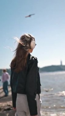 Portekiz, Lizbon 'da tagus nehri boyunca yürürken müziğin tadını çıkaran bir turist.