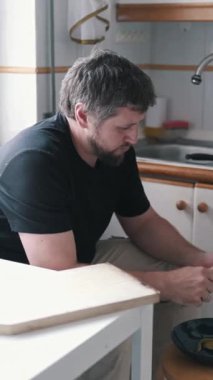 Adam mutfakta akvaryumla patates soyuyor.