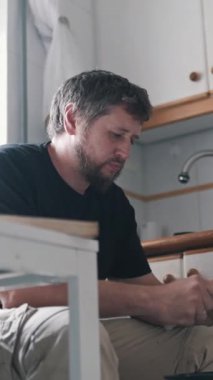 Ev mutfağında bıçakla mango soyan konsantre bir adam.