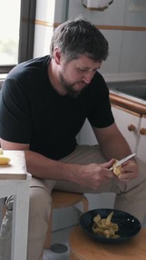 Evcil bir mutfakta patates soyan adam.