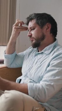 Sıkıcı adam pencerenin yanındaki kanepede kitap okuyor.