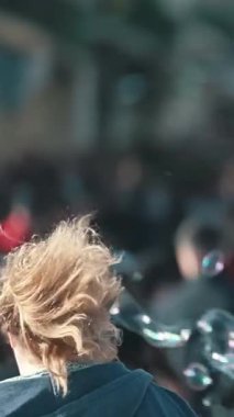 Sabun köpükleri, açık havada eğlenen büyük bir kalabalığın üzerinde yüzer.