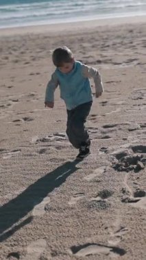 Okyanusun yakınındaki kumlu bir sahilde oynayan iki çocuk.