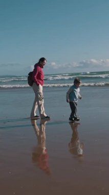 Baba ve oğul, güzel bir kumsalın ıslak kumu boyunca keyifle yürüyorlar.