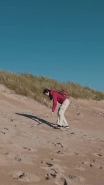 Mutlu anne ve oğul güneşli sahilde kumulda koşuyor.